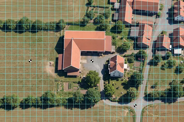 Illustratives Motiv: Orthofoto eines Bauernhofs von oben mit Messraster, nachgezeichneten Dachumrissen und Passpunkten