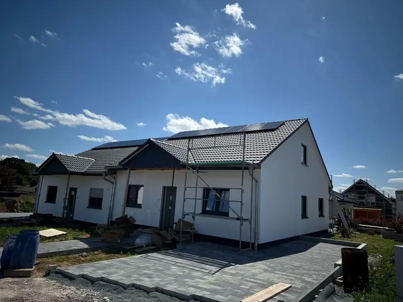 Neubau-Doppelhaus mit Gerüst und Solarmodulen auf dem Dach