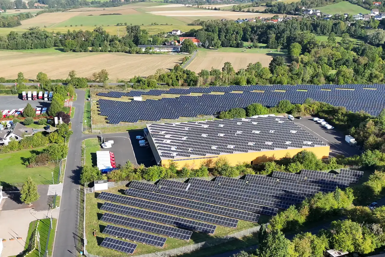 Logistikhalle mit Photovoltaikdach und angrenzenden Solarfeldern